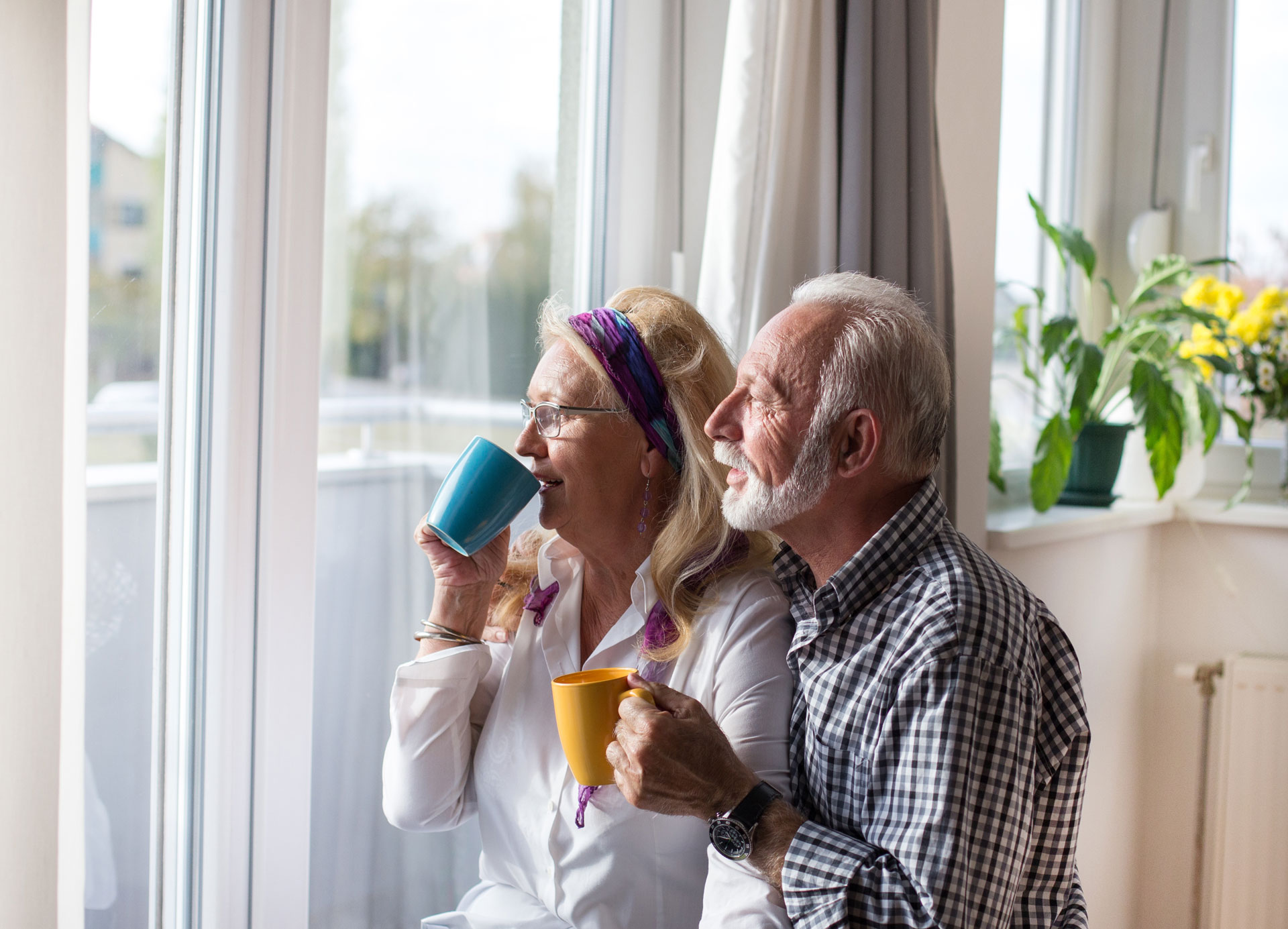 Älteres Paar genießt Kaffee am Fenster, entspannte Atmosphäre, Tageslicht beleuchtet Raum, harmonisches Beisammensein,