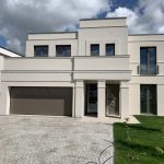 Markisen & Rollläden für Gewerbeobjekte in Berlin 3 Modernes, zweistöckiges Einfamilienhaus mit Flachdach, großer Garage und gepflegtem Garten bei bewölktem Himmel.