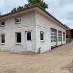Welche RC-Widerstandsklasse sollten Fenster? 11 Neubau eines modernen Gebäudes mit Flachdach, weißen Wänden und großen Garagentoren auf sandigem Grundstück.
